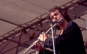 Ian McDonald of King Crimson and Foreigner playing a flute on stage in concert