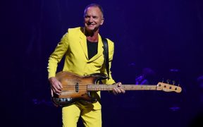 Sting with his bass guitar in a yellow suit on stage in concert in Las Vegas