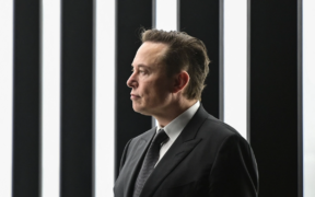 Elon Musk in a black suit and tie