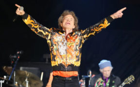 Mick Jagger wearing an orange jacket on stage