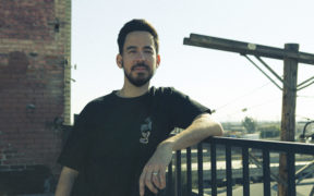 Mike Shinoda leaning on a railing wearing black tshirt