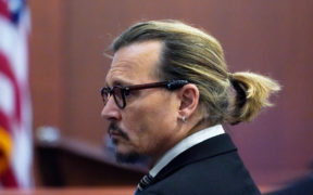 Johnny Depp watching in black suit and black glasses in court