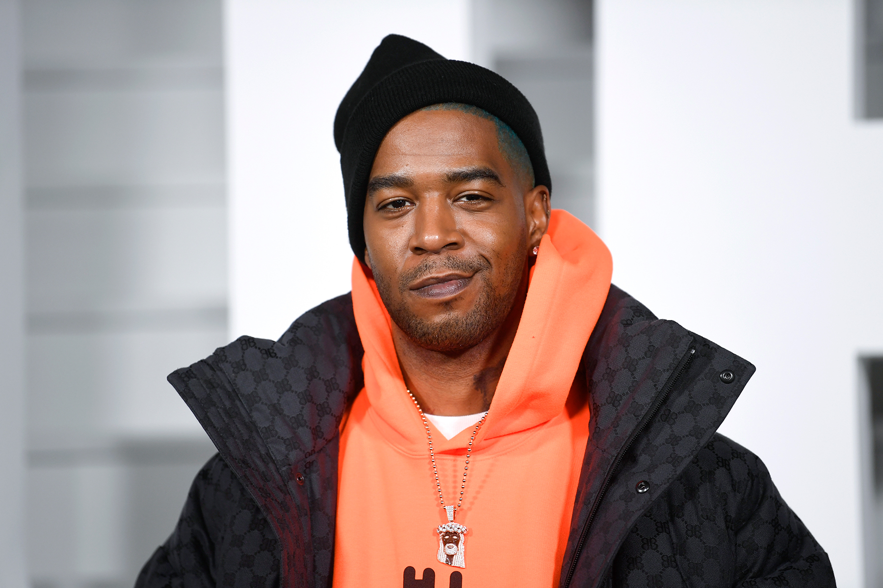 Kid Cudi in a black and orange jacket