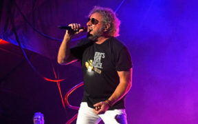 Sammy Hagar wearing black tshirt singing into mic on stage