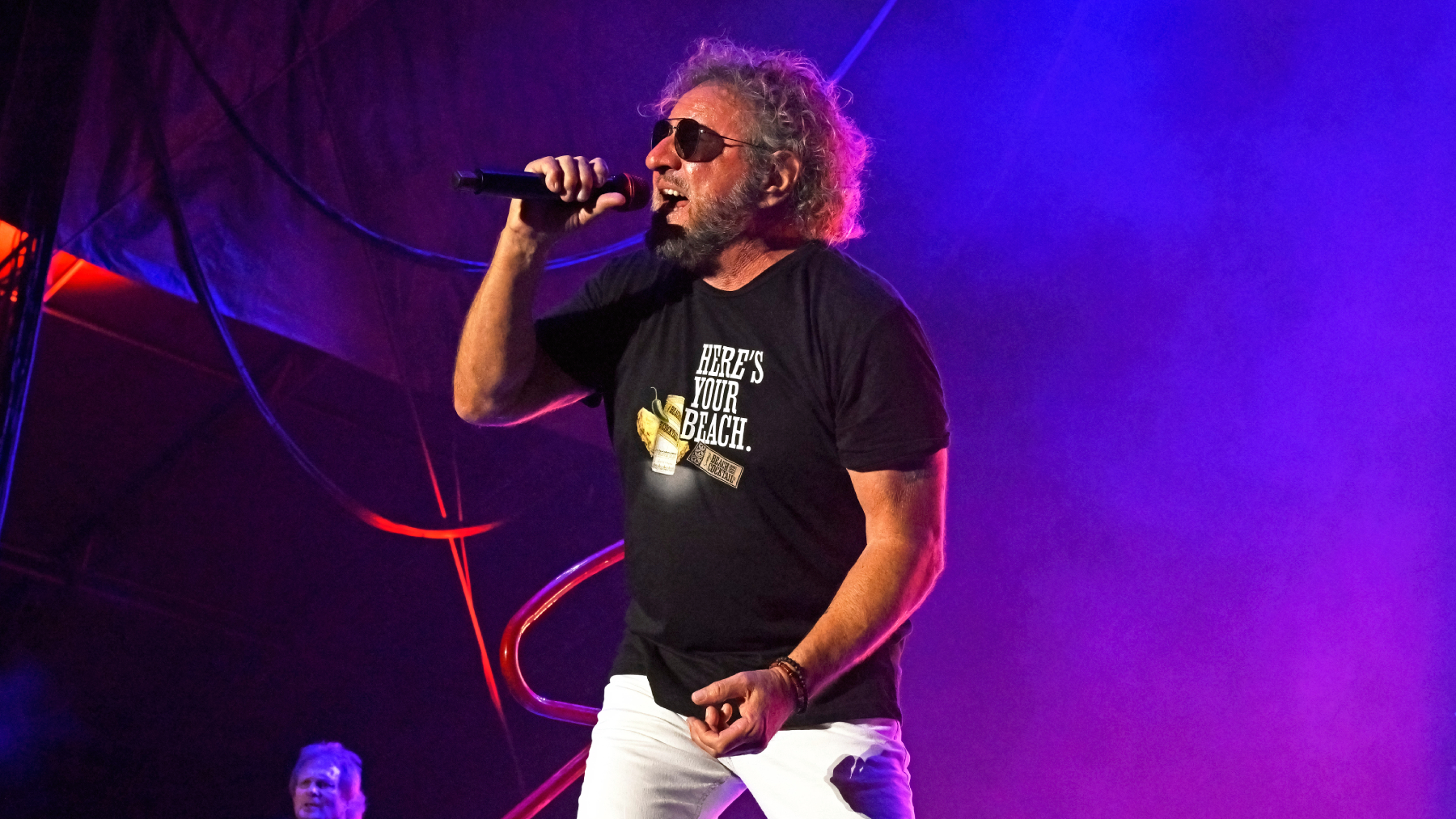 Sammy Hagar wearing black tshirt singing into mic on stage