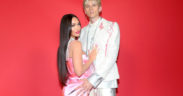 Megan Fox wearing a pink dress and holding Machine Gun Kelly in white suit