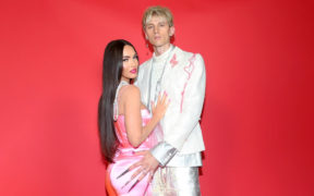 Megan Fox wearing a pink dress and holding Machine Gun Kelly in white suit