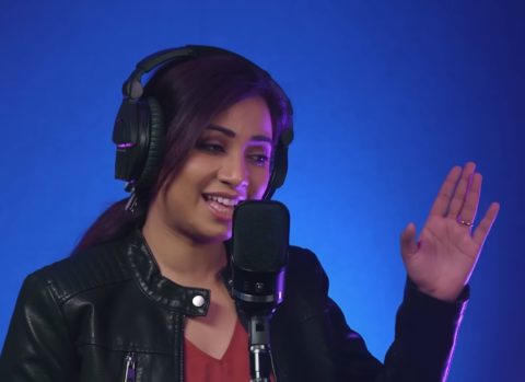 Shreya Ghoshal wearing headphones singing into mic