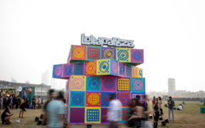 Attendees walk past a colorful installation with the Lollapalooza logo at Lollapalooza India music festival in Mumbai at Mahalaxmi Race course