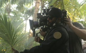 Ryan Coogler with a camera on the set in greenery for the movie Black Panther Wakanda Forever