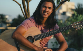 Tennis player Somdev Devvarman seated with an acoustic guitar