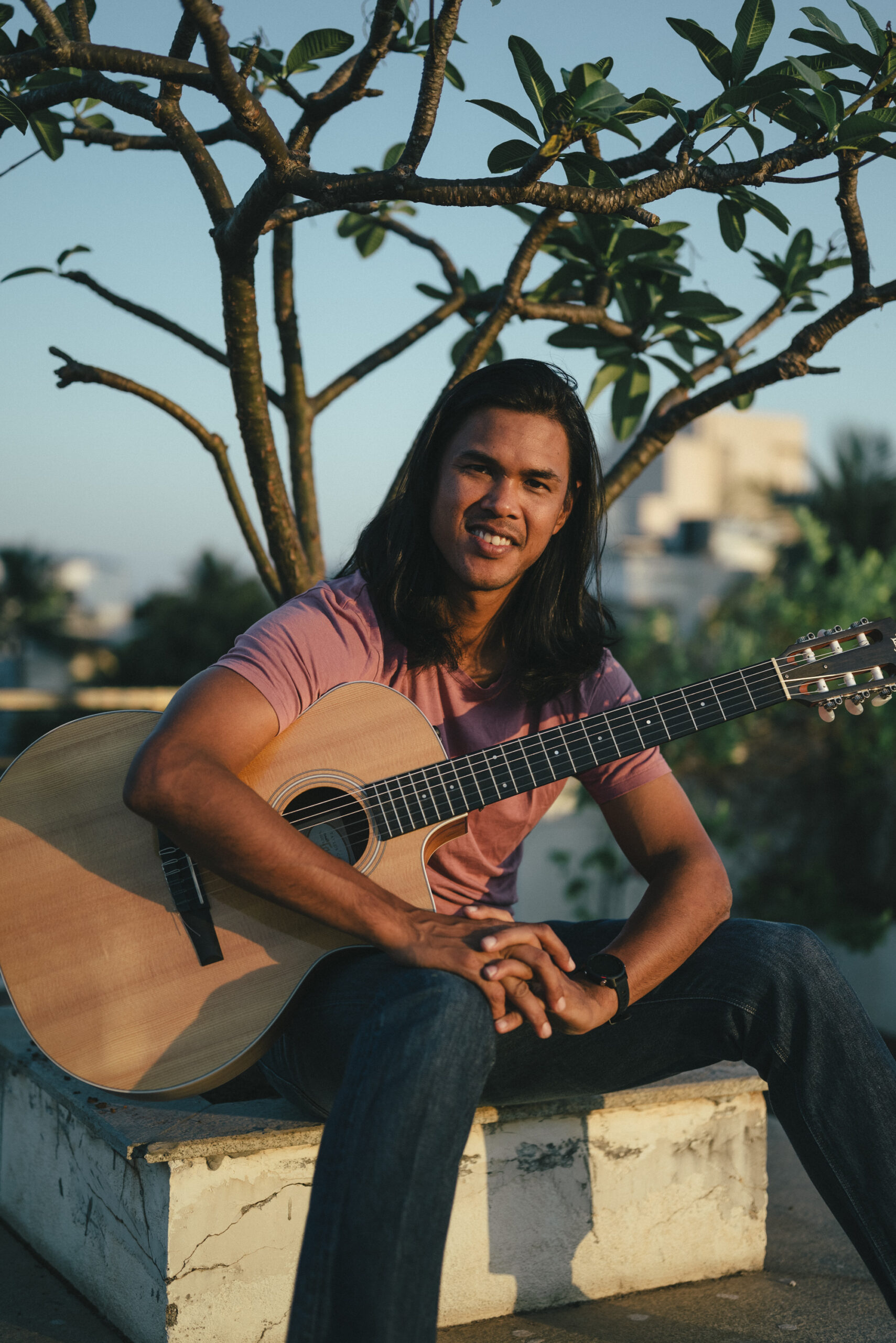 Tennis player Somdev Devvarman seated with an acoustic guitar