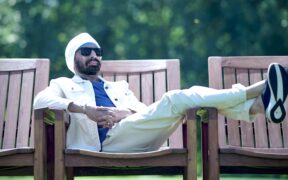 Vineet Singh Hukmani seated on a bench in a park in from his video for "Run! Run! Run!"