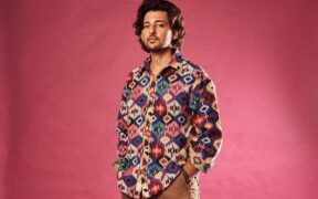 Darshan Raval in a multi color shirt posing with hands in pocket