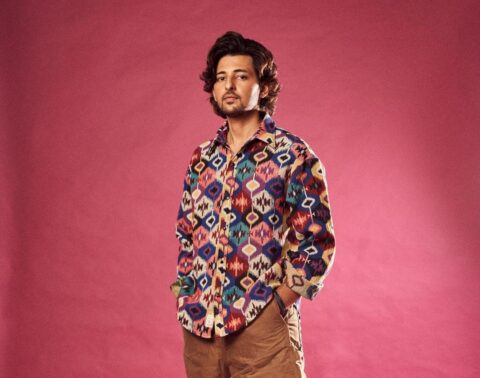 Darshan Raval in a multi color shirt posing with hands in pocket