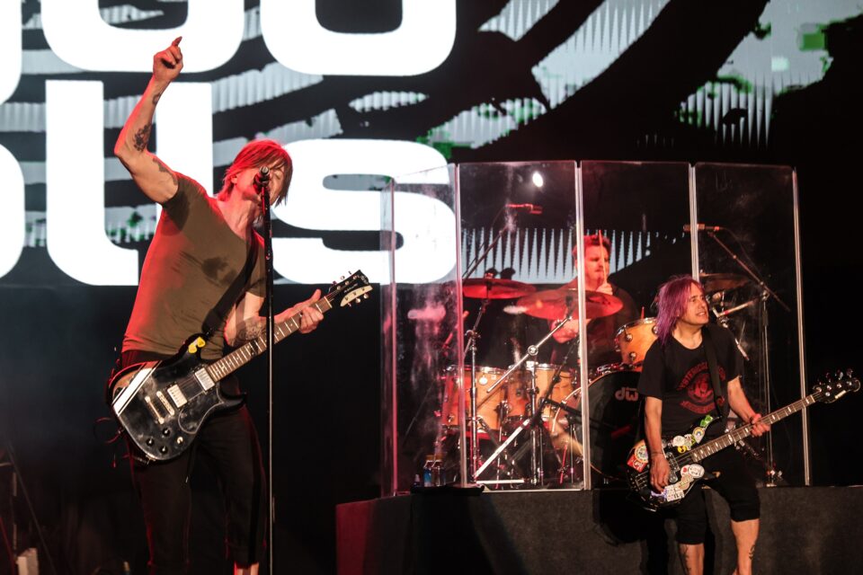 Rock band Goo Goo Dolls on stage with the vocalis raising his hand in the air