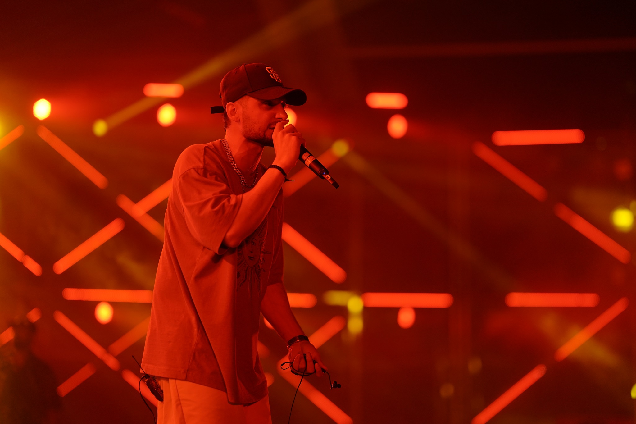 KR$NA performing on stage with mic in hand, wearing cap