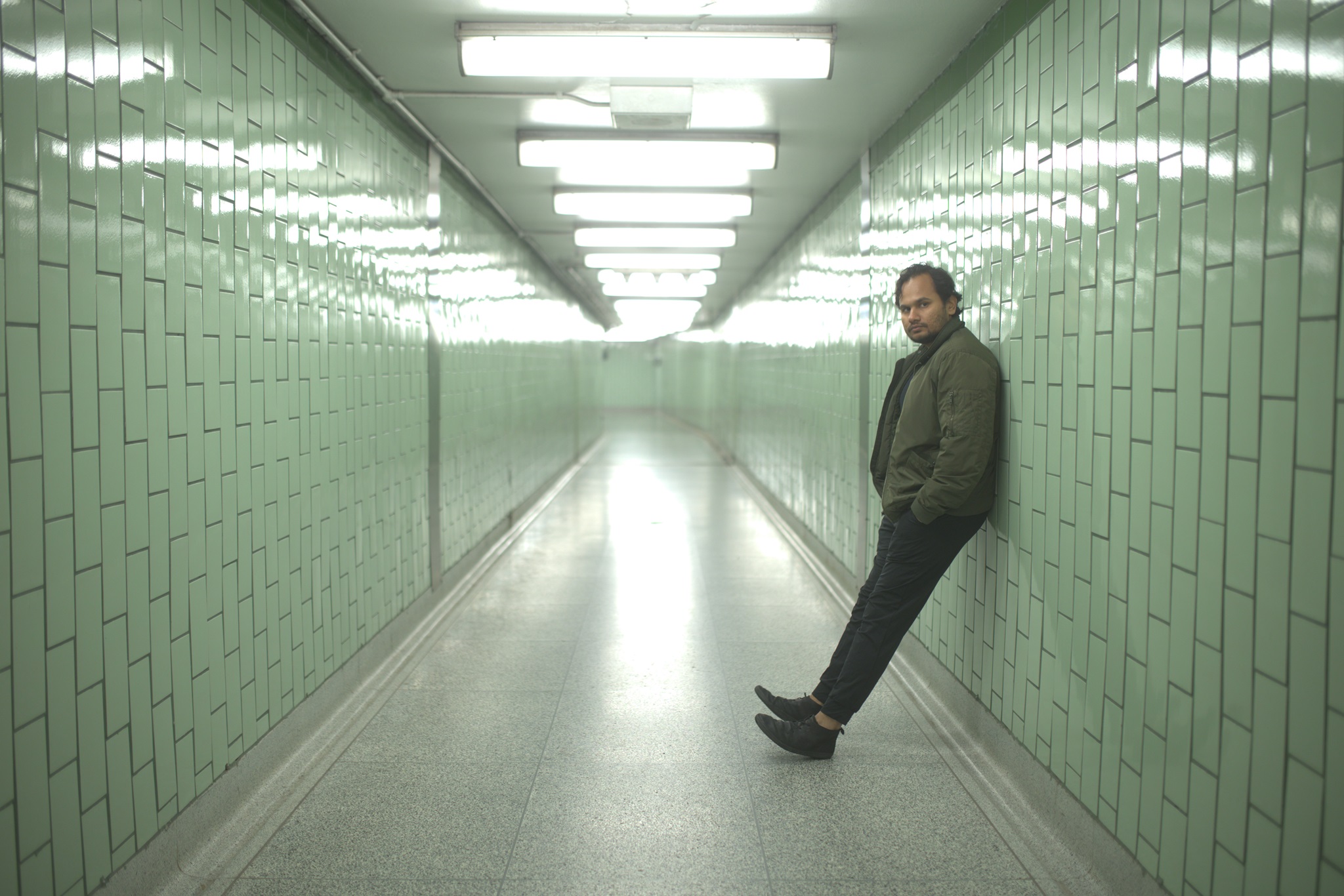 Kaber Vasuki leaning on a wall in a tunnel with tubelights