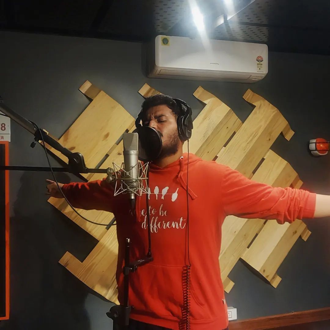 Hyderabad rapper 2much aka Sushel Peraboina in the studio wearing a red t-shirt recording in front of a mic