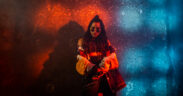 Singer Nikhita Gandhi wearing glasses and posing in red and blue light