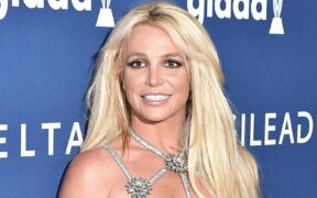 Britney Spears smiling and posing for photos in a silver dress