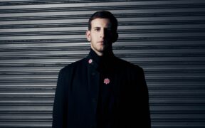 DJ and producer Illenium in a black suit looking at camera