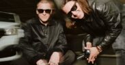 Tom McFarland and Josh Lloyd-Watson of the UK band Jungle wearing black outfits and sunglasses, looking into the camera