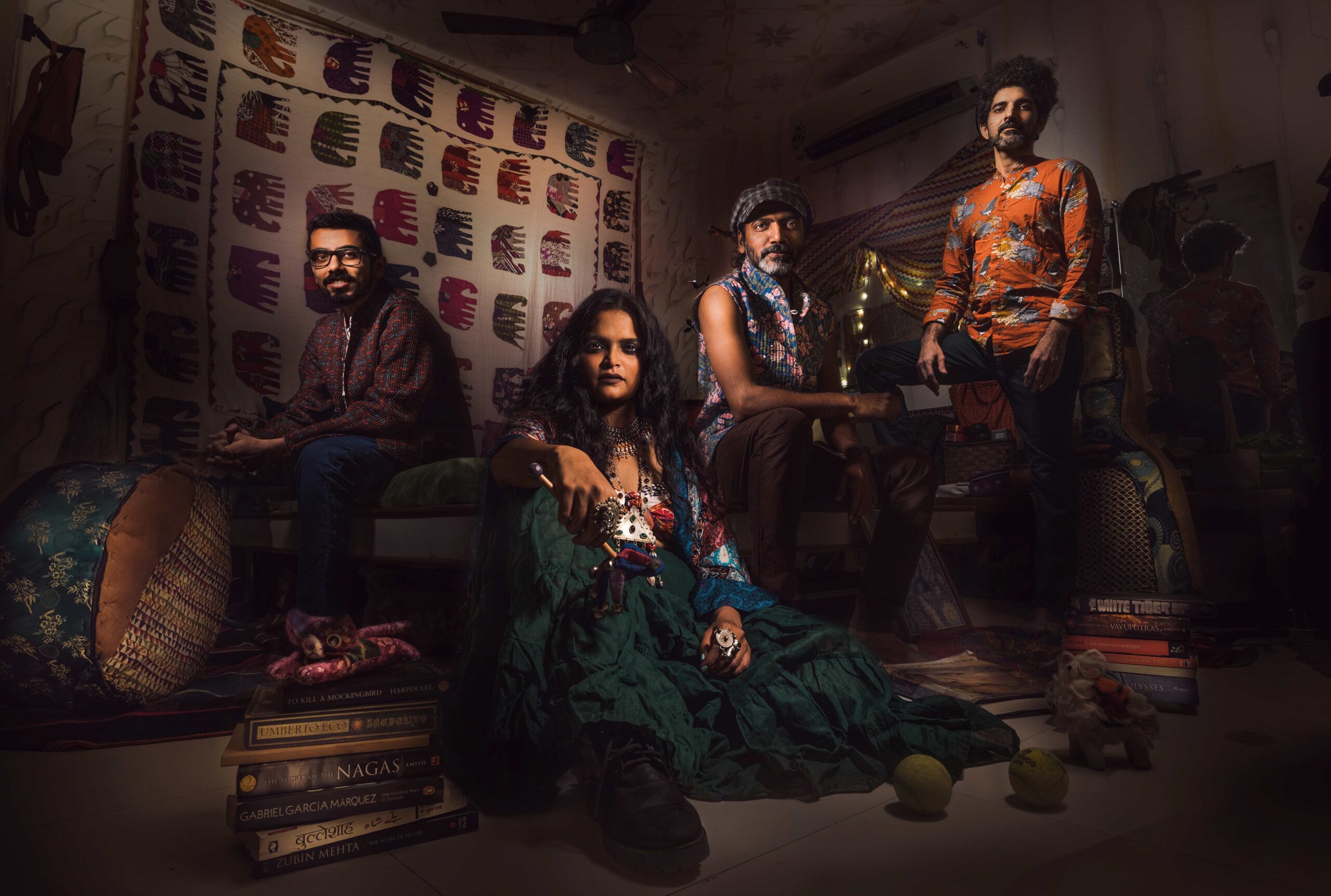 Band members of Surat rock act The Tapi Project pose for a photo in a dark room wearing colorful clothes