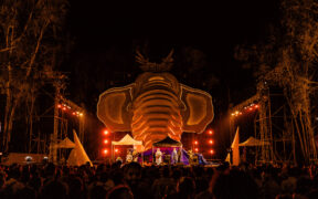 Tinariwen on stage with an elephant sculpture in the background at Echoes of Earth music festival