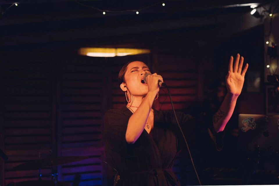 Artist Yuhina singing on stage in a black dress