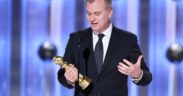 Christopher Nolan wearing a black suit accepting Golden Globe award