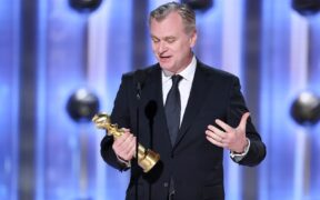 Christopher Nolan wearing a black suit accepting Golden Globe award