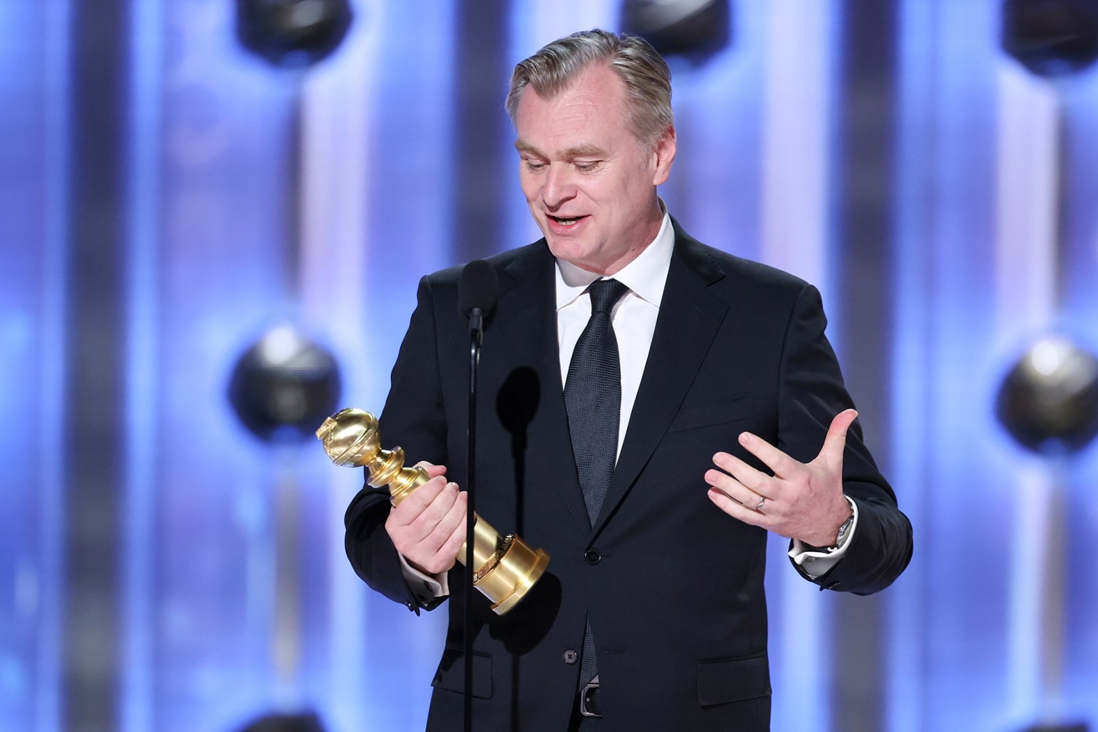 Christopher Nolan wearing a black suit accepting Golden Globe award