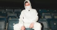 Alan Walker wearing all white seated on a chair