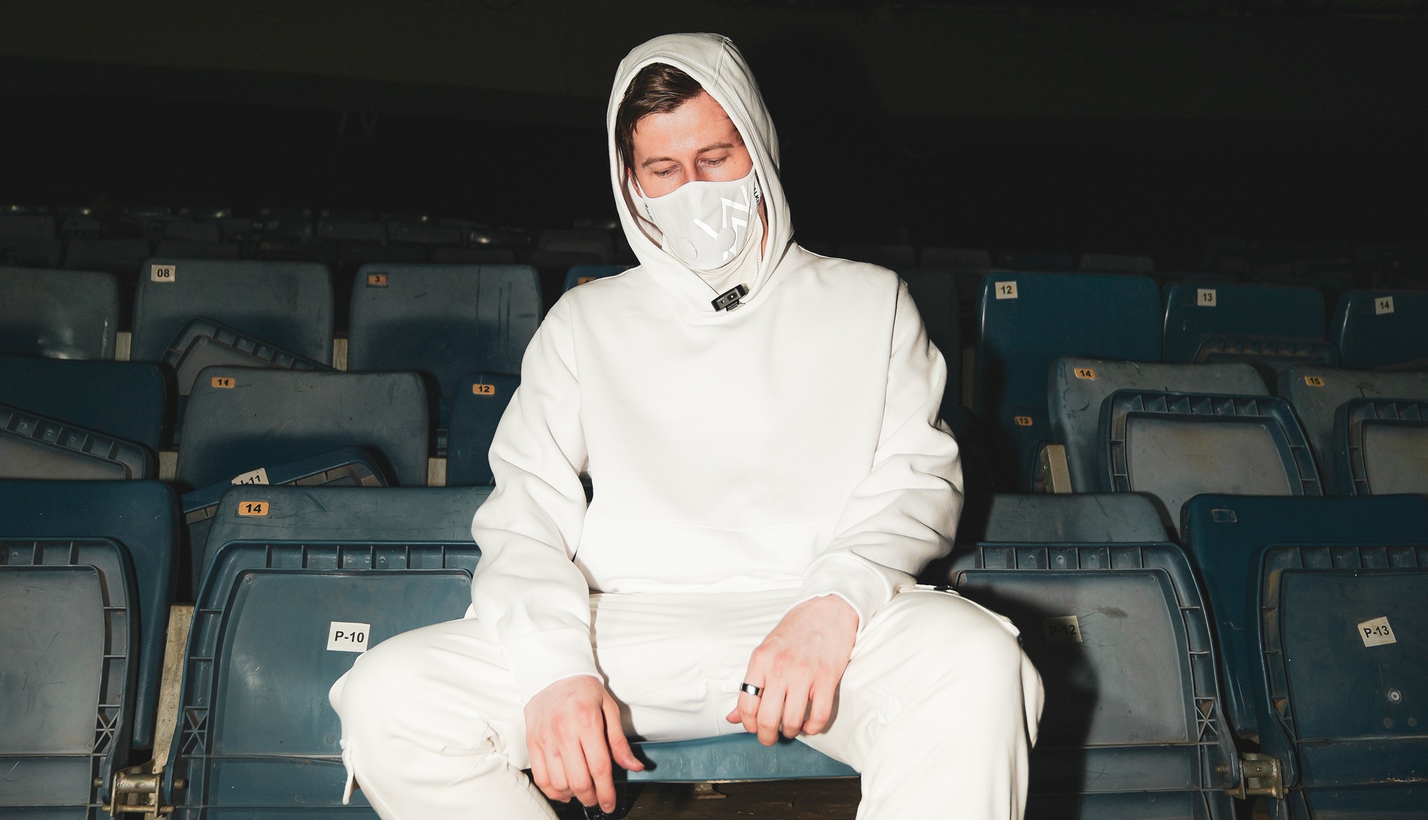 Alan Walker wearing all white seated on a chair