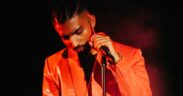 Rapper Gravity in an orange suit holding a mic