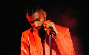 Rapper Gravity in an orange suit holding a mic