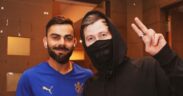 Virat Kohli smiling with DJ Alan Walker in black wearing mask