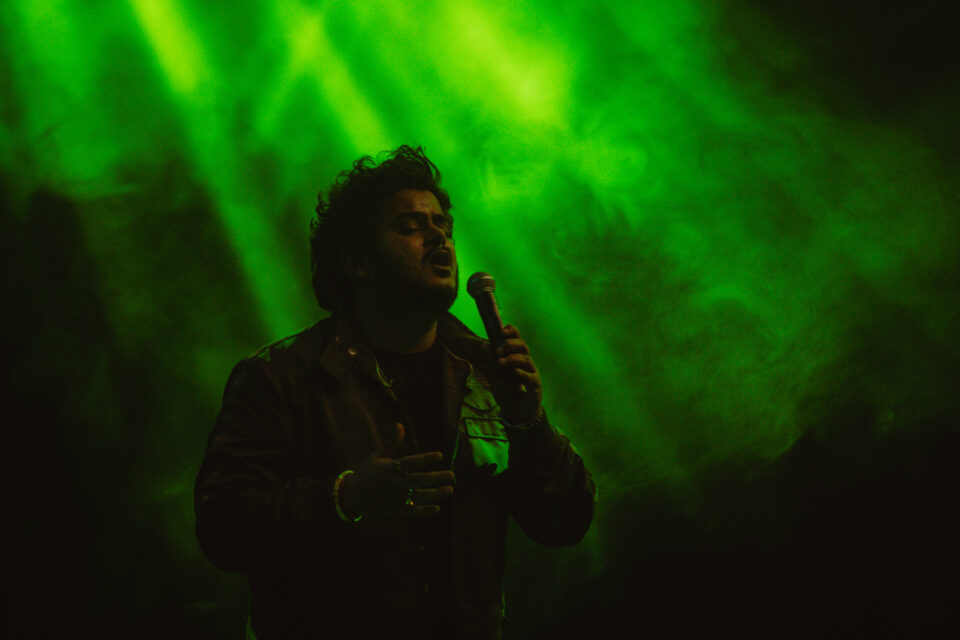 Vishal Mishra in a green light background holding a mic