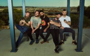 Karnivool band members sitting under a shelter posing for a photo