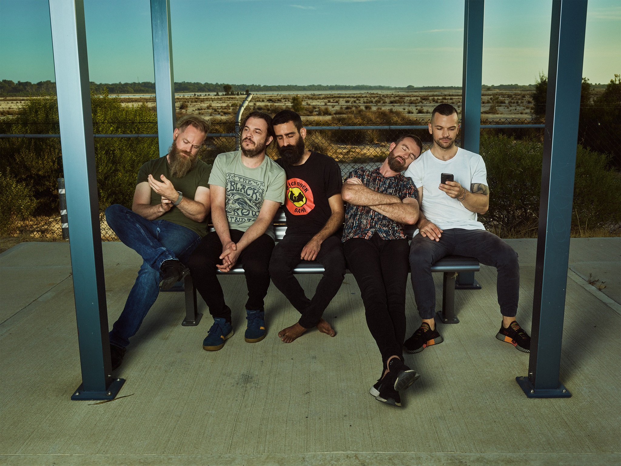 Karnivool band members sitting under a shelter posing for a photo