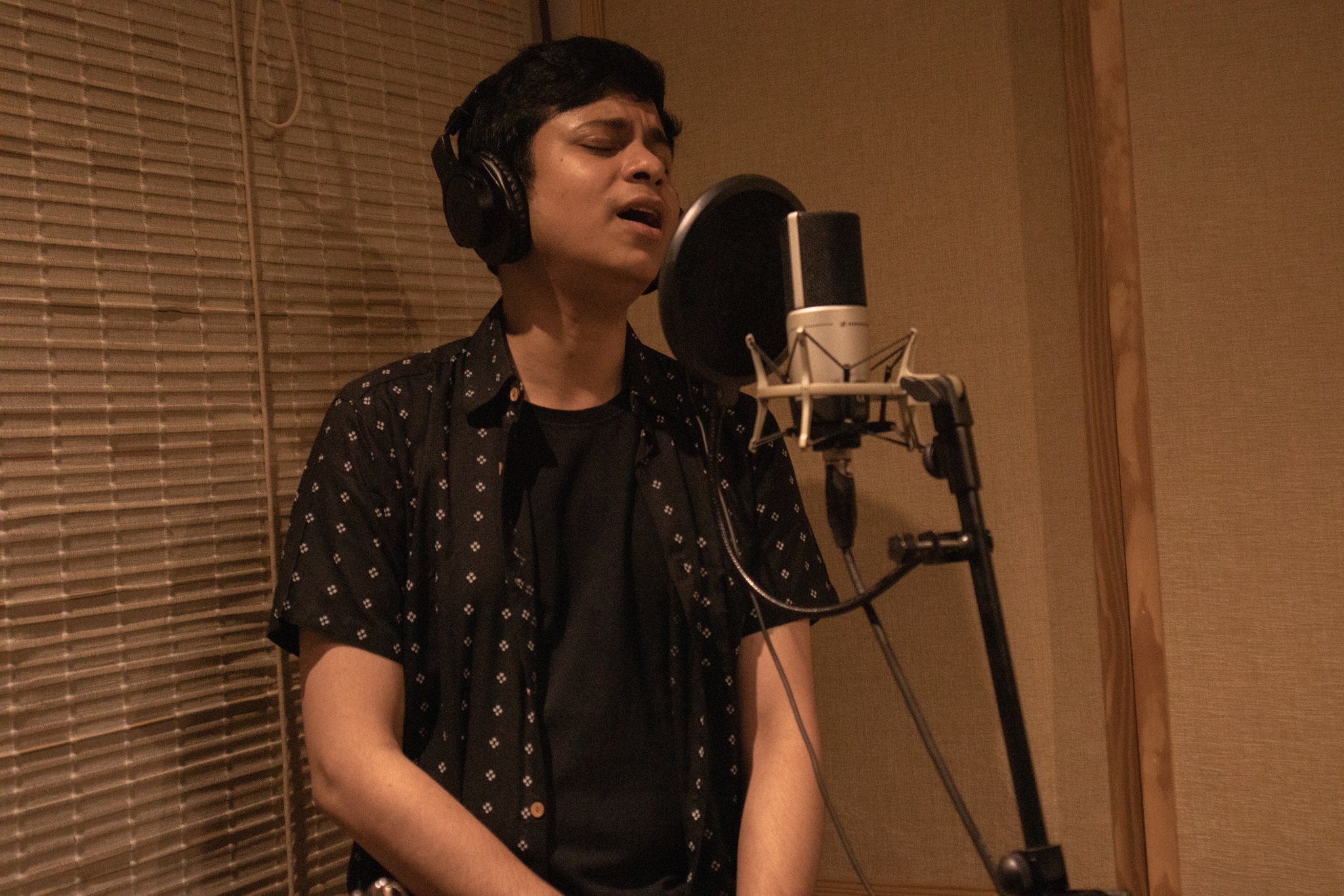 Sourav Dey singing into a mic in a recording studio.