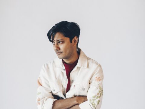 Mumbai singer-songwriter Tejas wearing white jacket and a red tshirt with arms crossed
