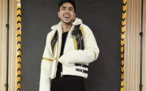 Actor Adarsh Gourav smiling, wearing an oversized white jacket and black trousers