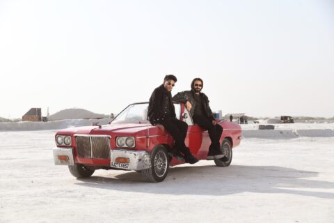 Guru Randhawa and Babbu Maan sitting on a red convertible car in the Pagal music video