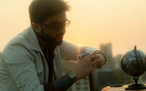 Kidshot in a white jacket, wearing glasses and looking at a globe in city backdrop