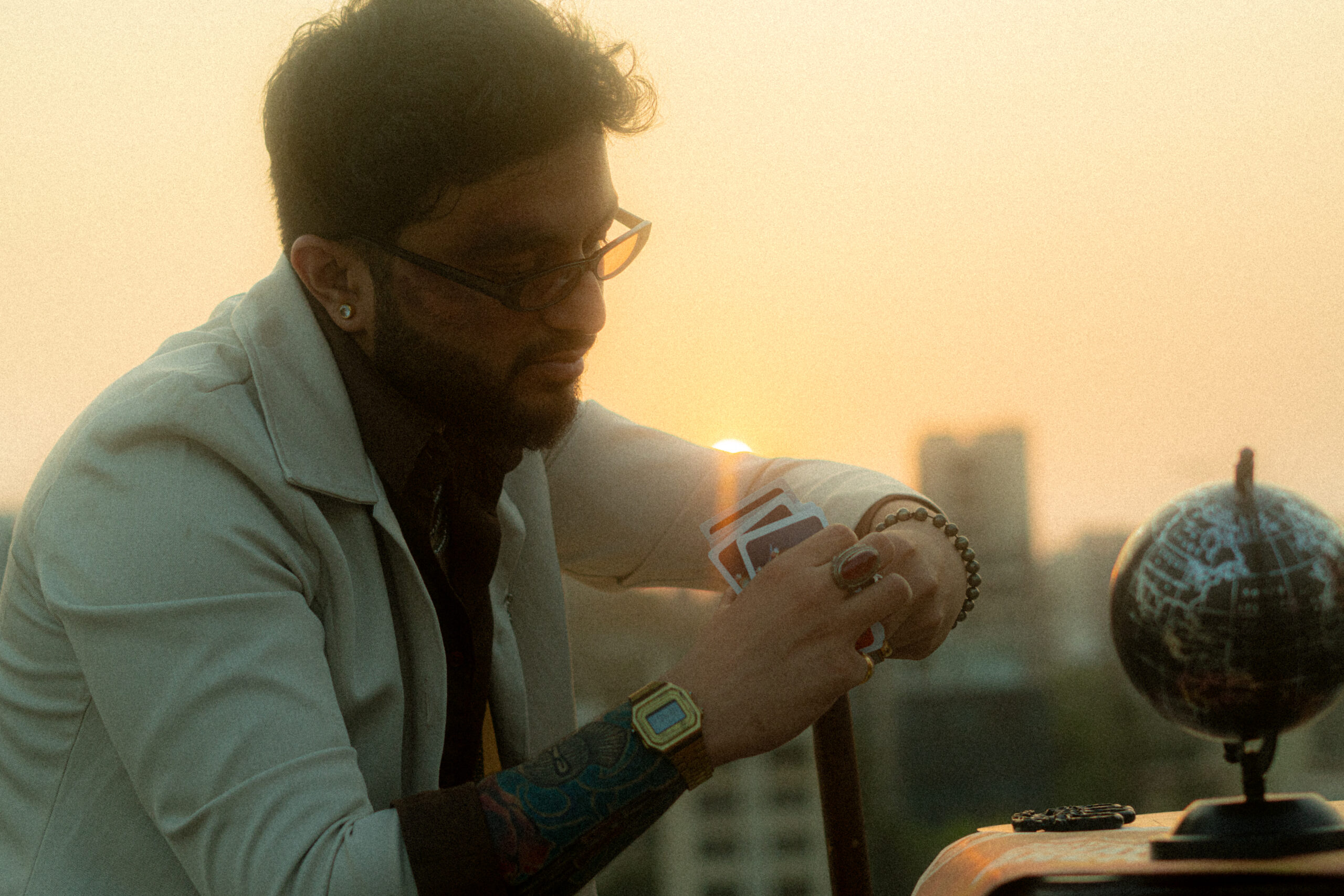 Kidshot in a white jacket, wearing glasses and looking at a globe in city backdrop