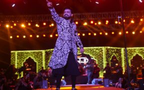 Sagar Bhatia performing on stage, in a white and black outfit, pointing out