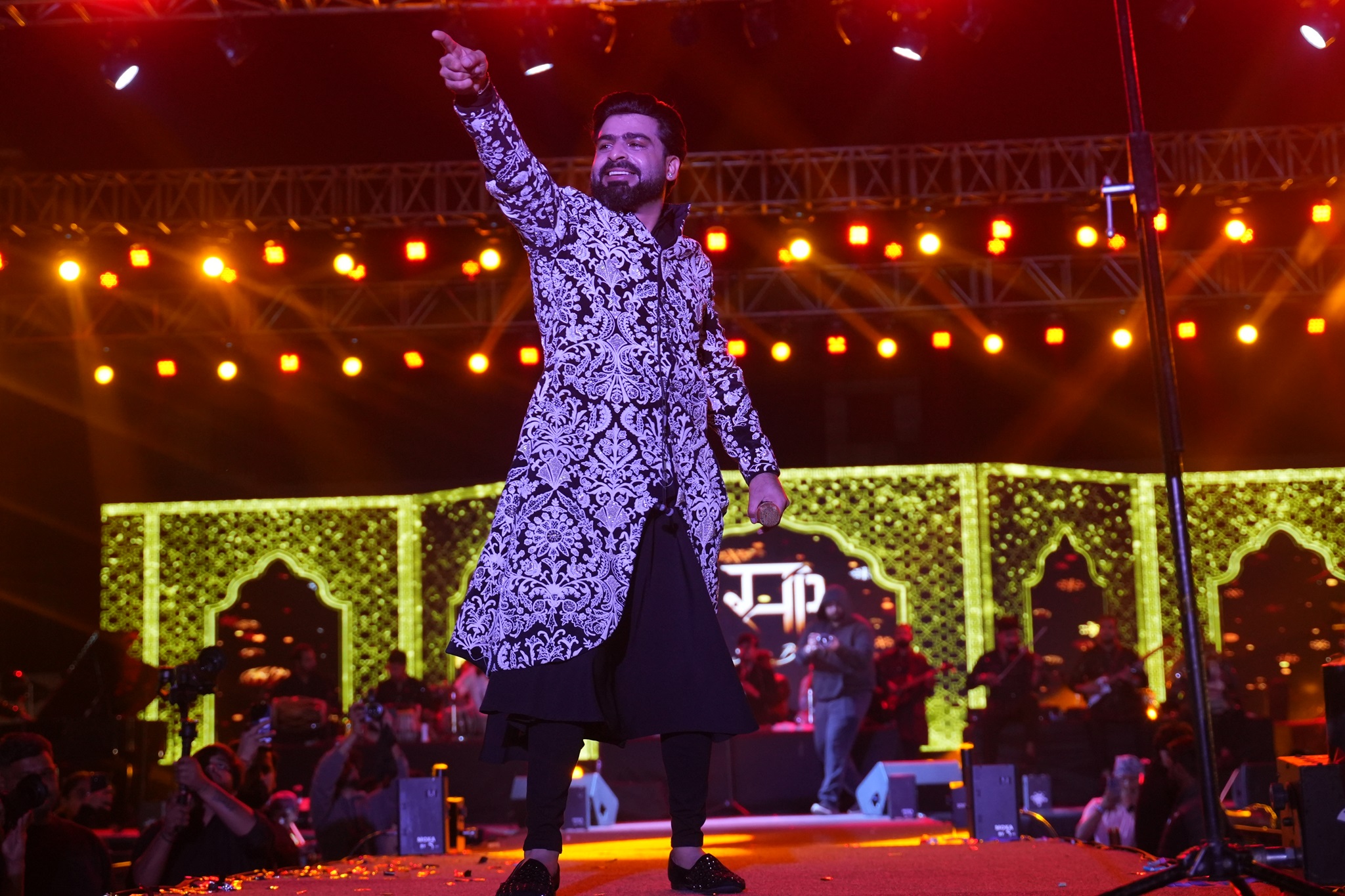 Sagar Bhatia performing on stage, in a white and black outfit, pointing out