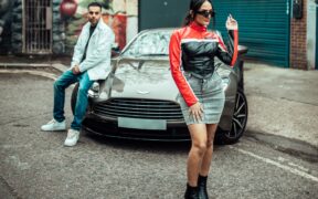 H Dhami and Saloni standing near an Aston Martin car in a music video shoot